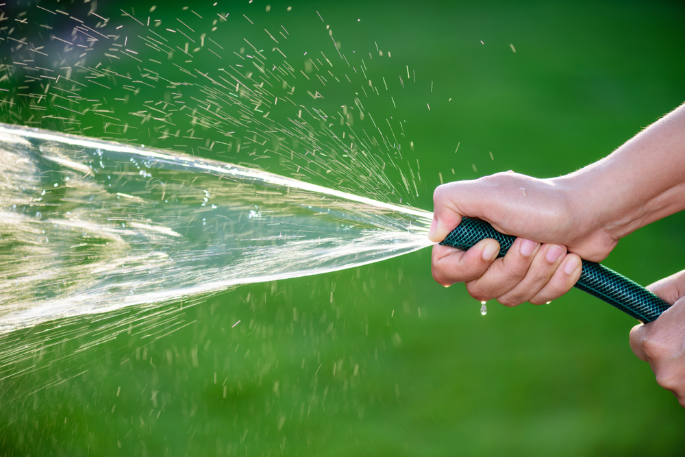 Person spraying a garden hose outside in San Jose, CA