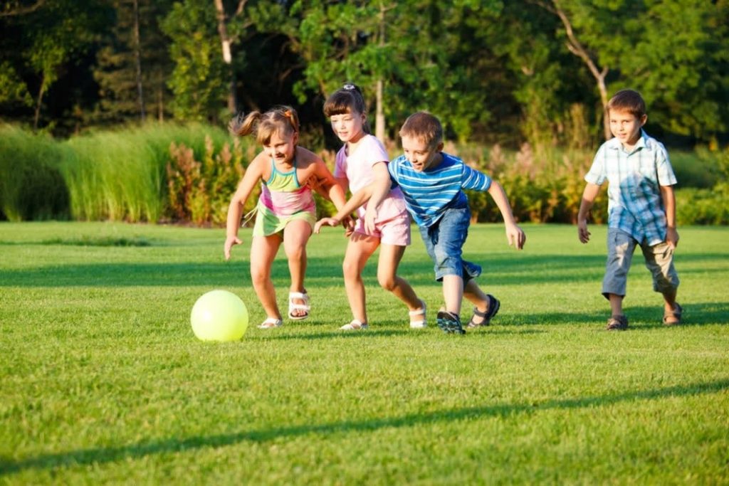 Kids playing with a ball on artificial grass.