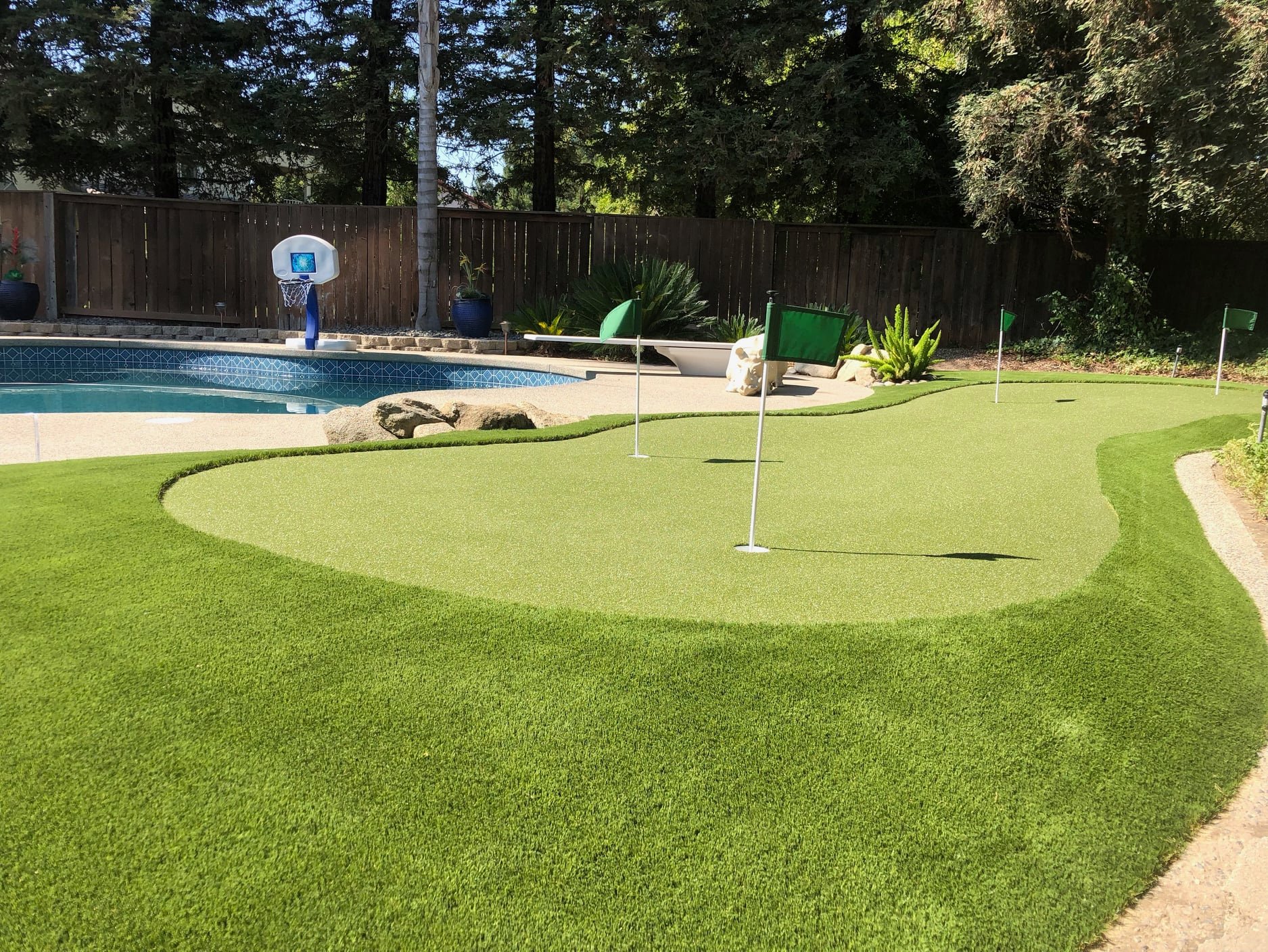 An artificial putting green in a Silicon Valley backyard with a pool.